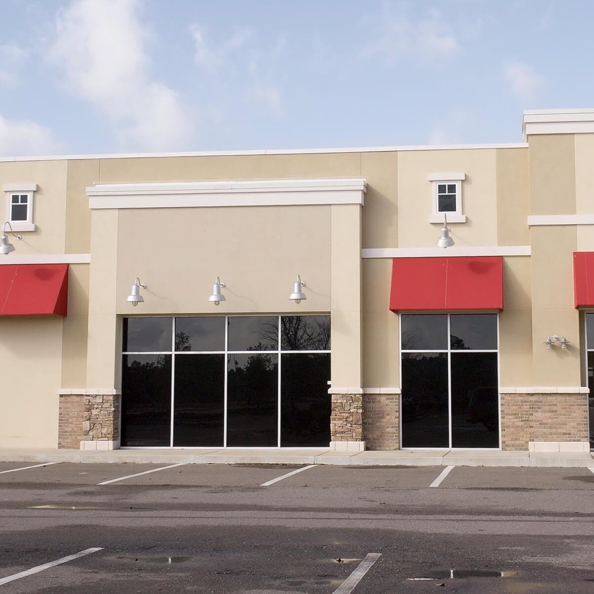 upscale pastel strip mall building with red awnings and tinted glass